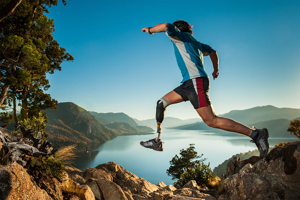 A prosthesis wearer jumps over rocks