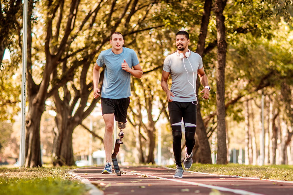 Zwei männer laufen auf einer Laufstrecke, einer trägt eine Sportprothese