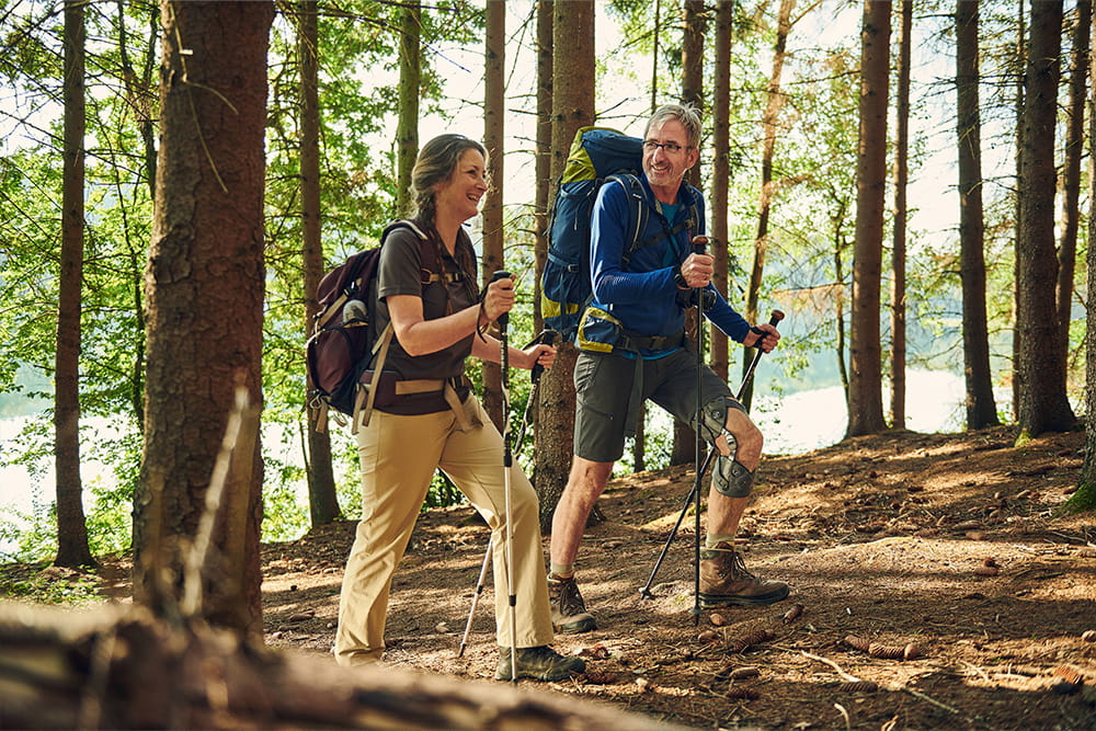 A woman and a man with leg orthosis walking in a forest