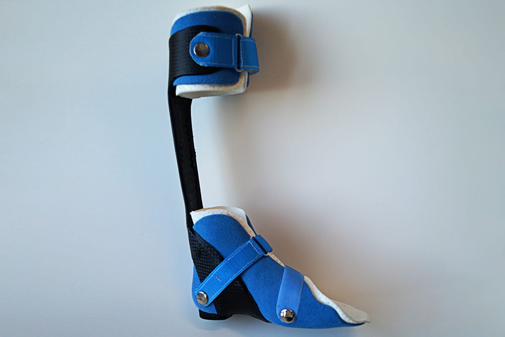 Side view of a blue and black orthosis on a gray background.
