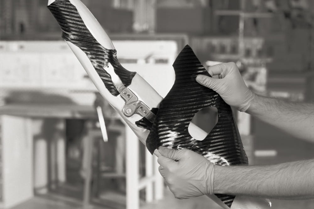 A technician pulls a layer of carbon onto an orthosis.