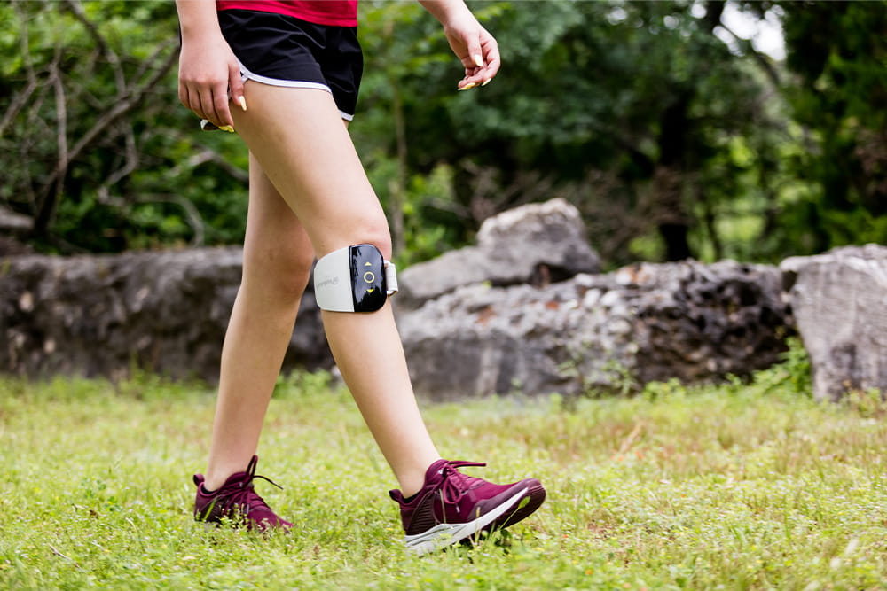 Eine Frau beim gehen die unter ihrem Knie ein elektrisches Gerät zur elektrostimulation trägt