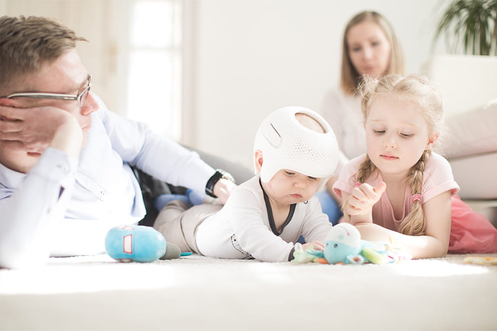 A family of four plays with the baby on the floor