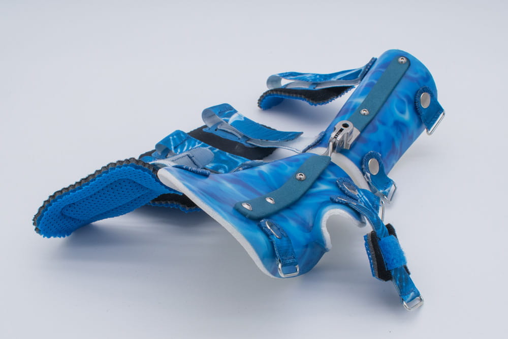 A hand orthosis in blue lying on a table with the fasteners open.