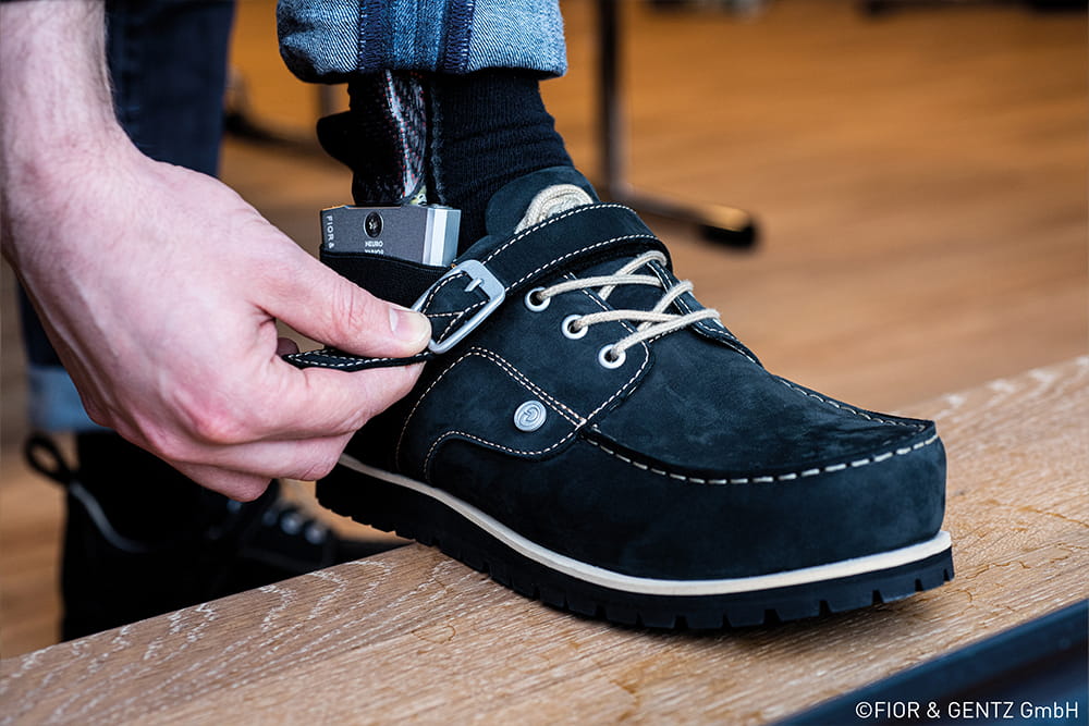 Ein Mann trägt Orthesenschuhe und ist gerade dabei, den Verschluss zu schließen.