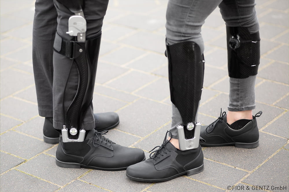 Zwei Personen mit Beinorthesen stehen beieinander.