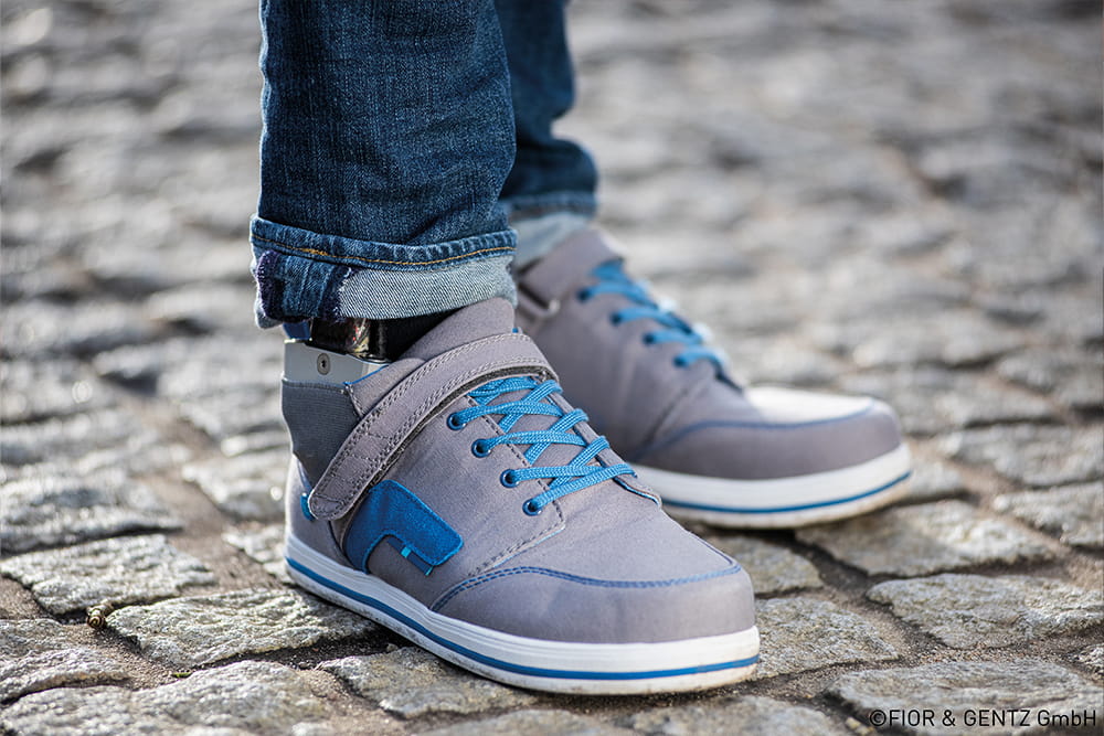 Nahaufnahme von blau grauen Schuhen, die zu einer Beinorthese passen.