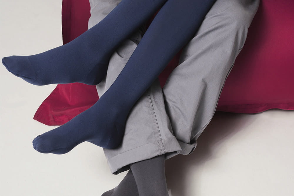 Zwei Personen mit Kompressionsstrümpfen von medi legen die Beine übereinander.