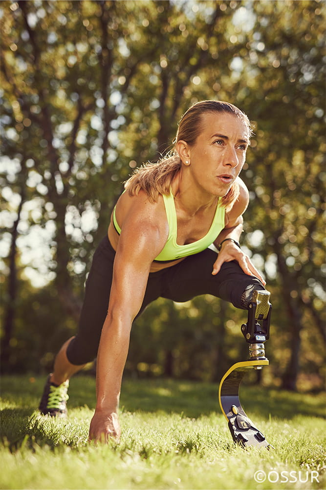 Eine Frau mit Beinprothese dehnt sich nach dem Sport.