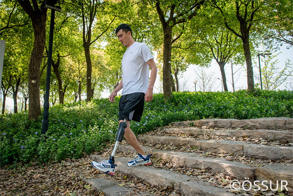 Ein Mann mit Beinprothese steigt Treppen in einem Park runter.
