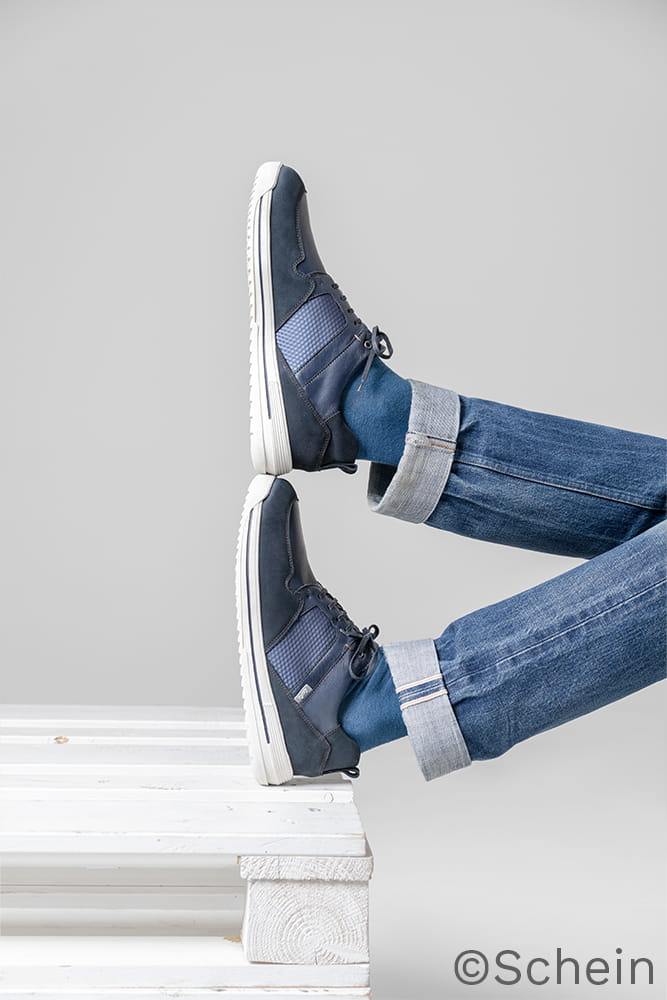 Zwei Füße in Schuhen sind aufeinander abgestellt und ruhen auf einer weißen Palette.