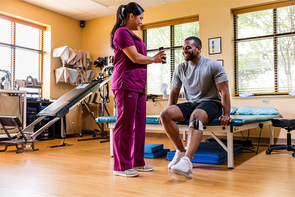 Ein Mann mit Neuro-Orthese wird gerade für den Sport optimal über das Smartphone eingestellt.