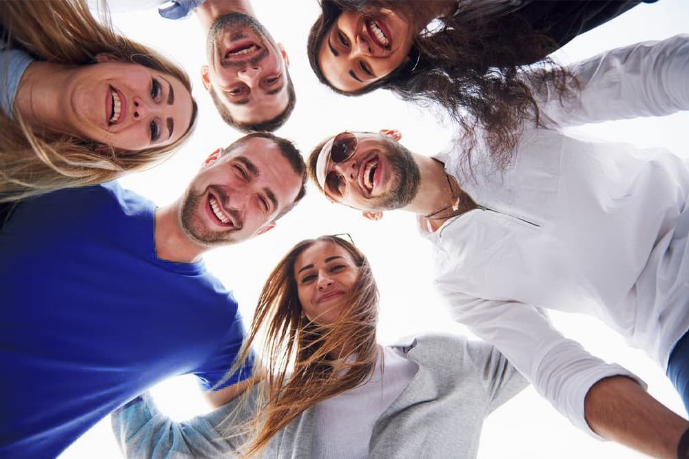 Eine Gruppe von Meschen steht im Kreis und alle schauen gemeinsam nach unten.